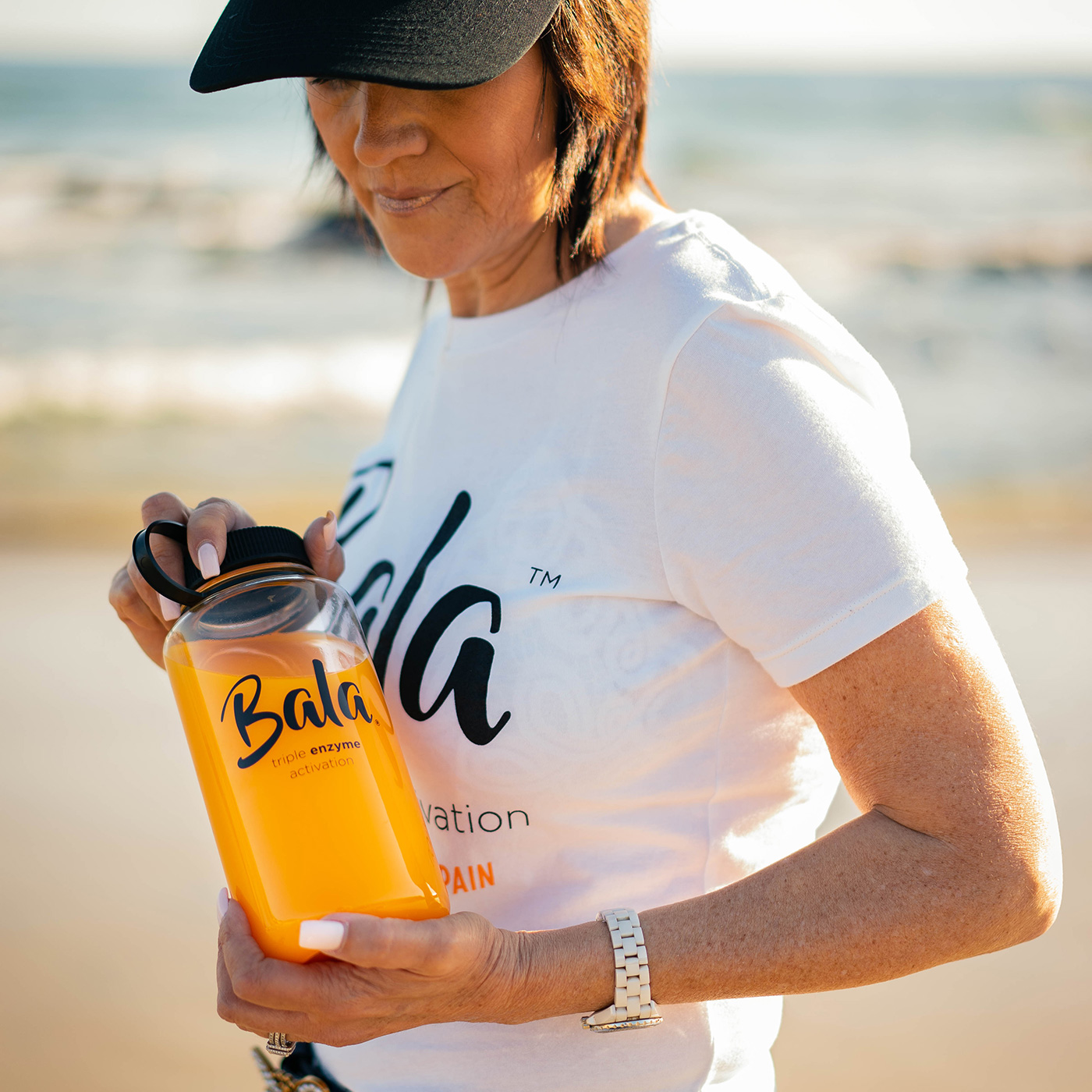 woman holding bottle of Bala on the beach